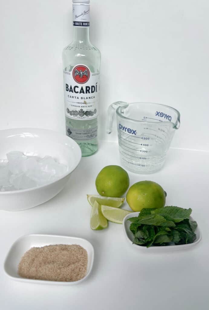 Ingredients to make a mojito on a white bench top.