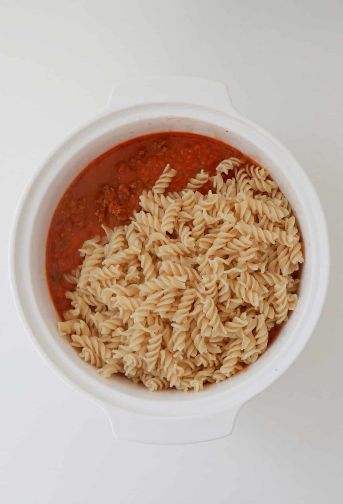Pasta and sauce in a white baking dish.