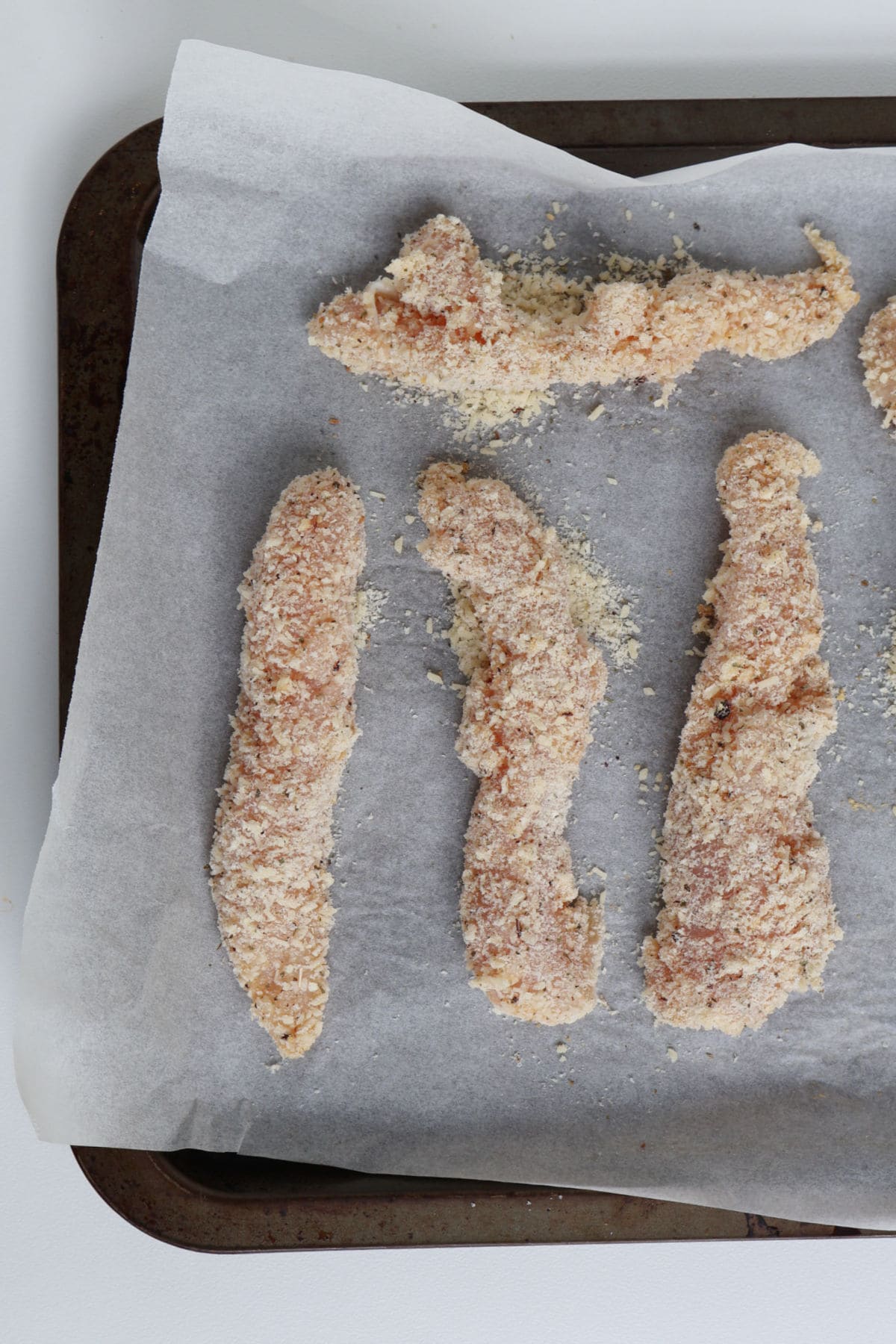 Uncooked chicken tenders on a baking tray.