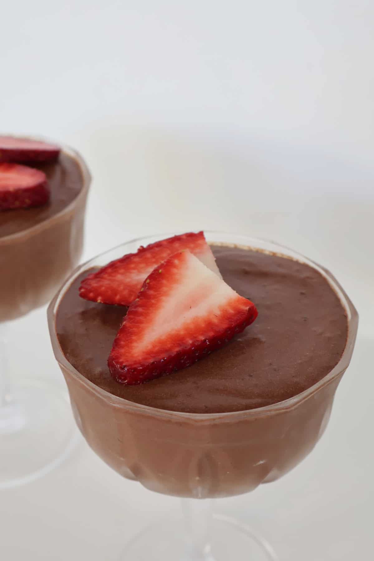 Side view of chocolate mousse topped with strawberries in a glass.