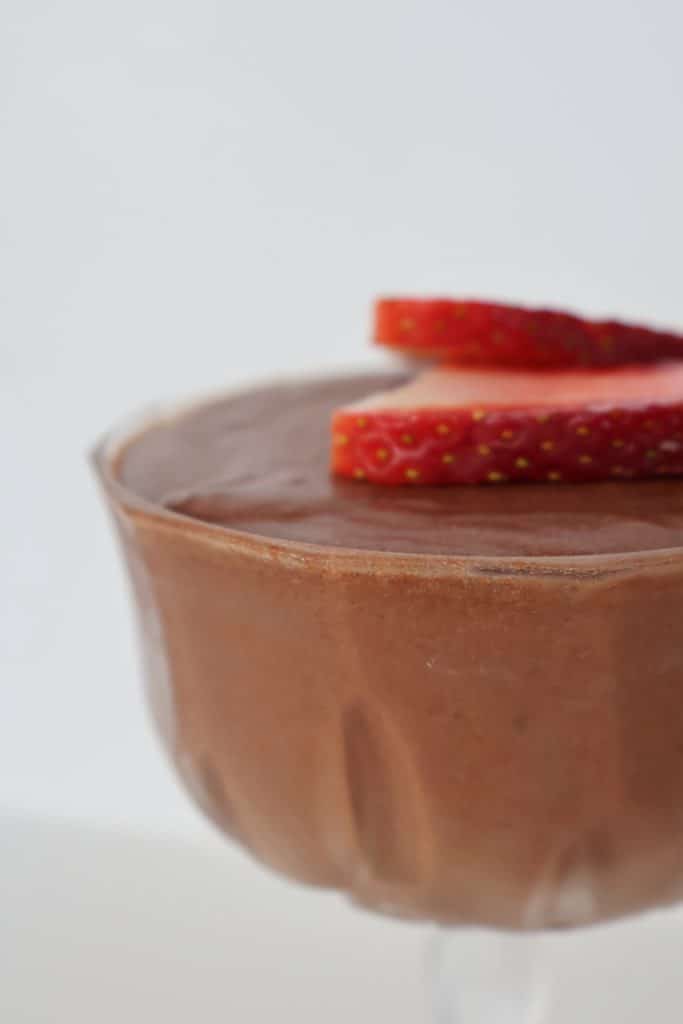 Side view of chocolate mousse topped with strawberries in a glass.