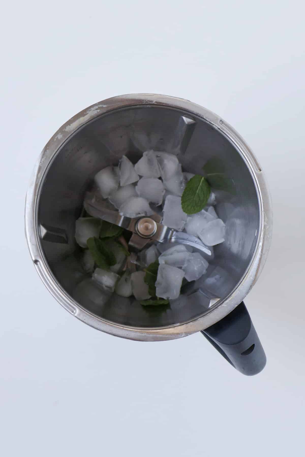 Ice and mint leaves in a thermomix bowl.