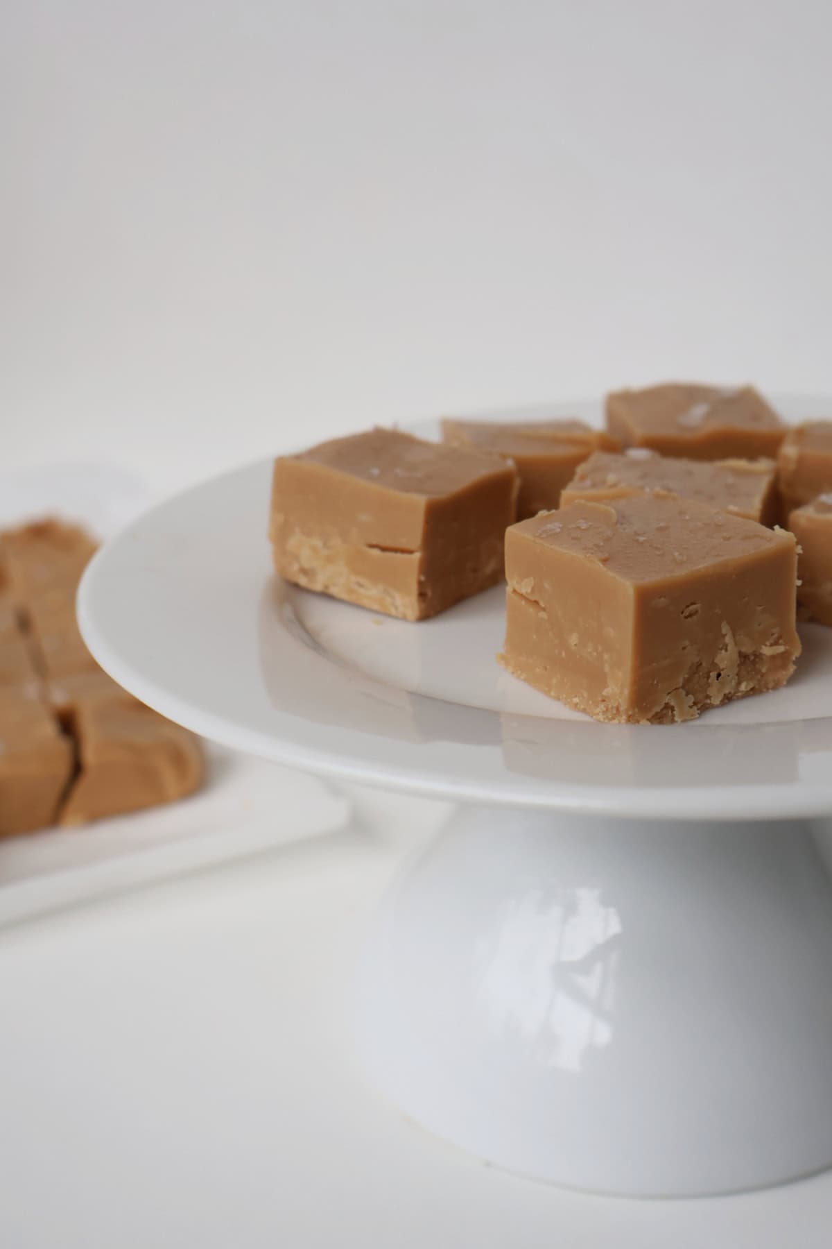 White cake plate topped with pieces of salted caramel fudge.