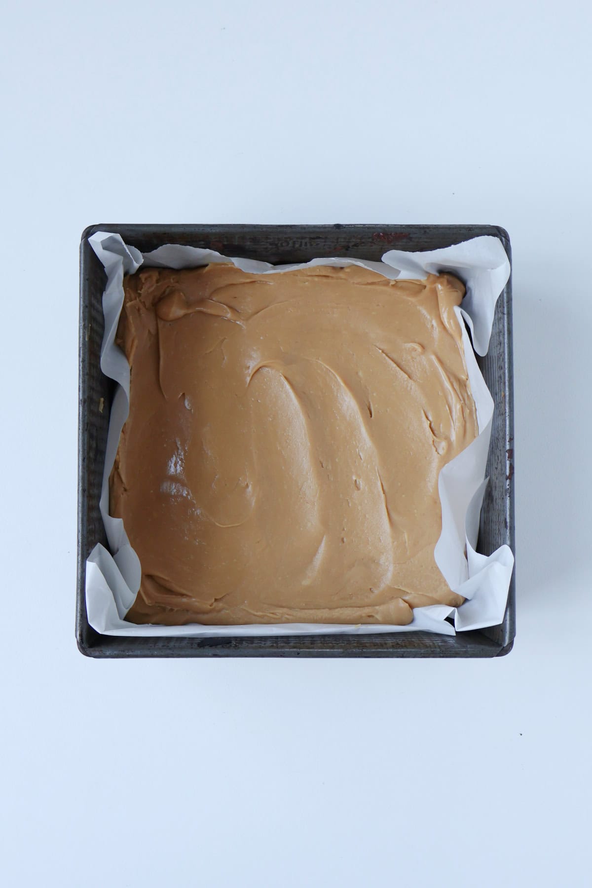 Salted caramel fudge mixture poured into a baking dish before extra salt added.