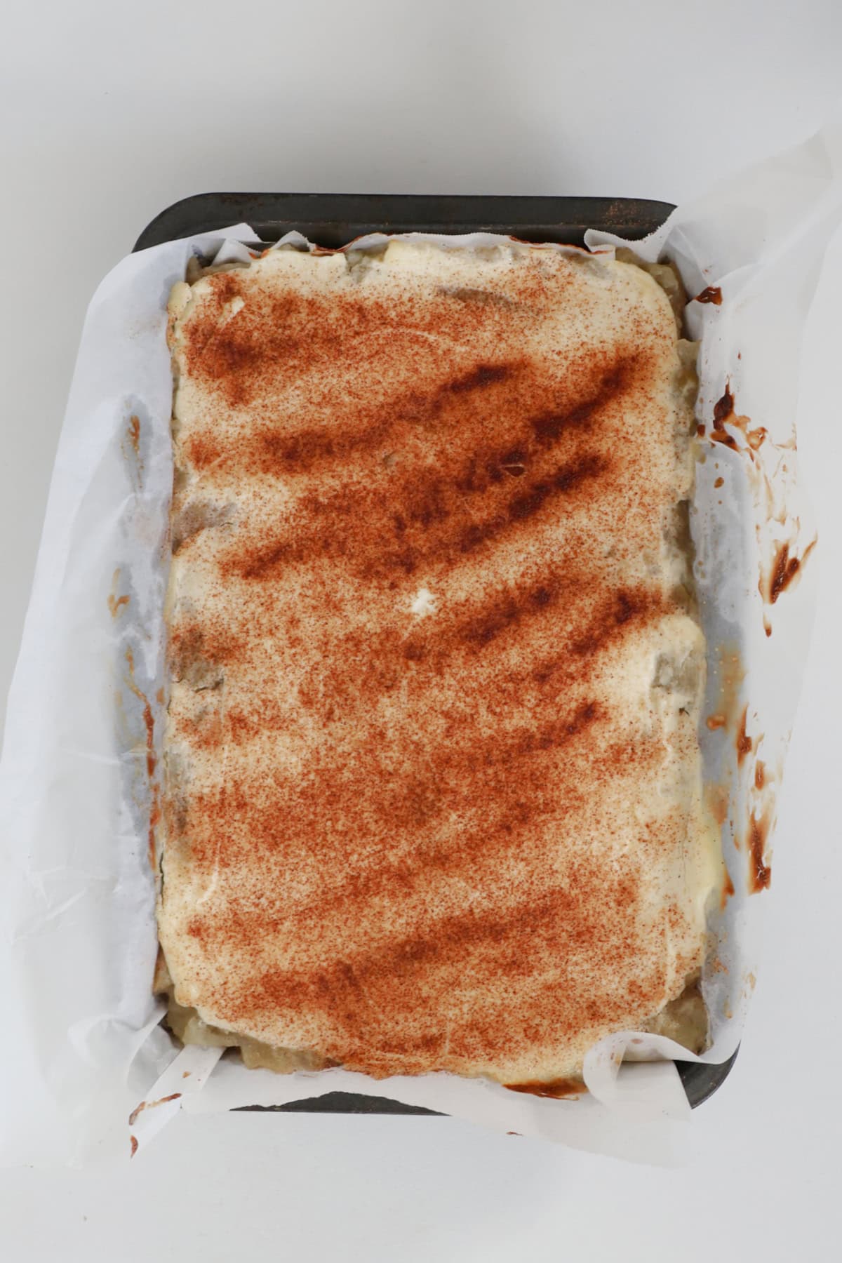 Overhead view of Slices of Apple and Sour Cream Slice in baking dish.