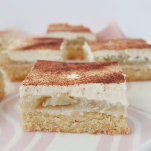 front view of Slices of Apple and Sour Cream Slice sitting on a pink striped plate.