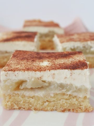 front view of Slices of Apple and Sour Cream Slice sitting on a pink striped plate.