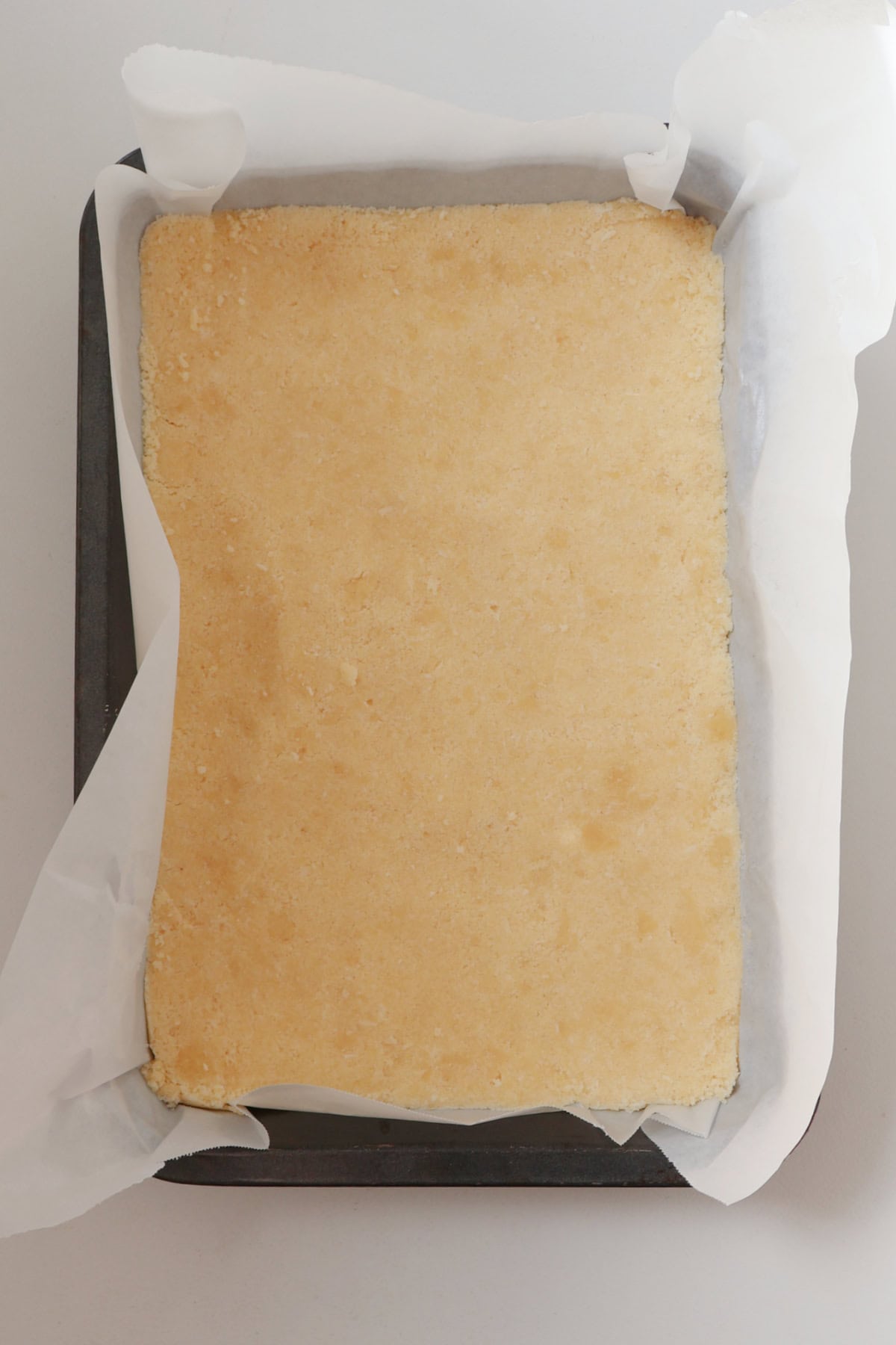 Baked base of apple and sour cream slice.