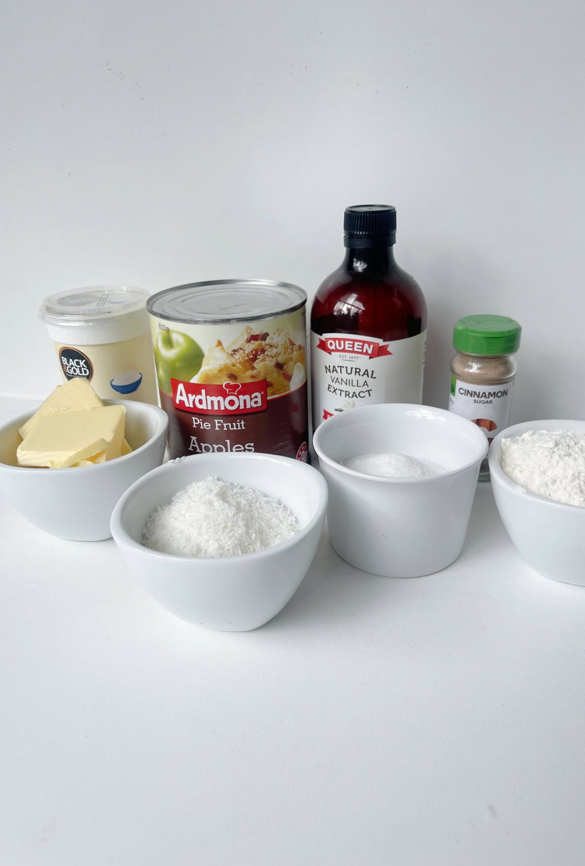 Ingredients to make an apple and sour cream slice sitting on white bench.