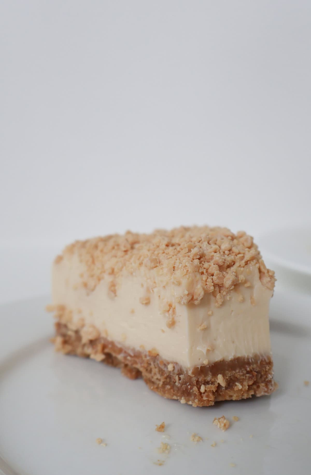 Slice of caramilk cheesecake on a white plate with a piece taken out of it.